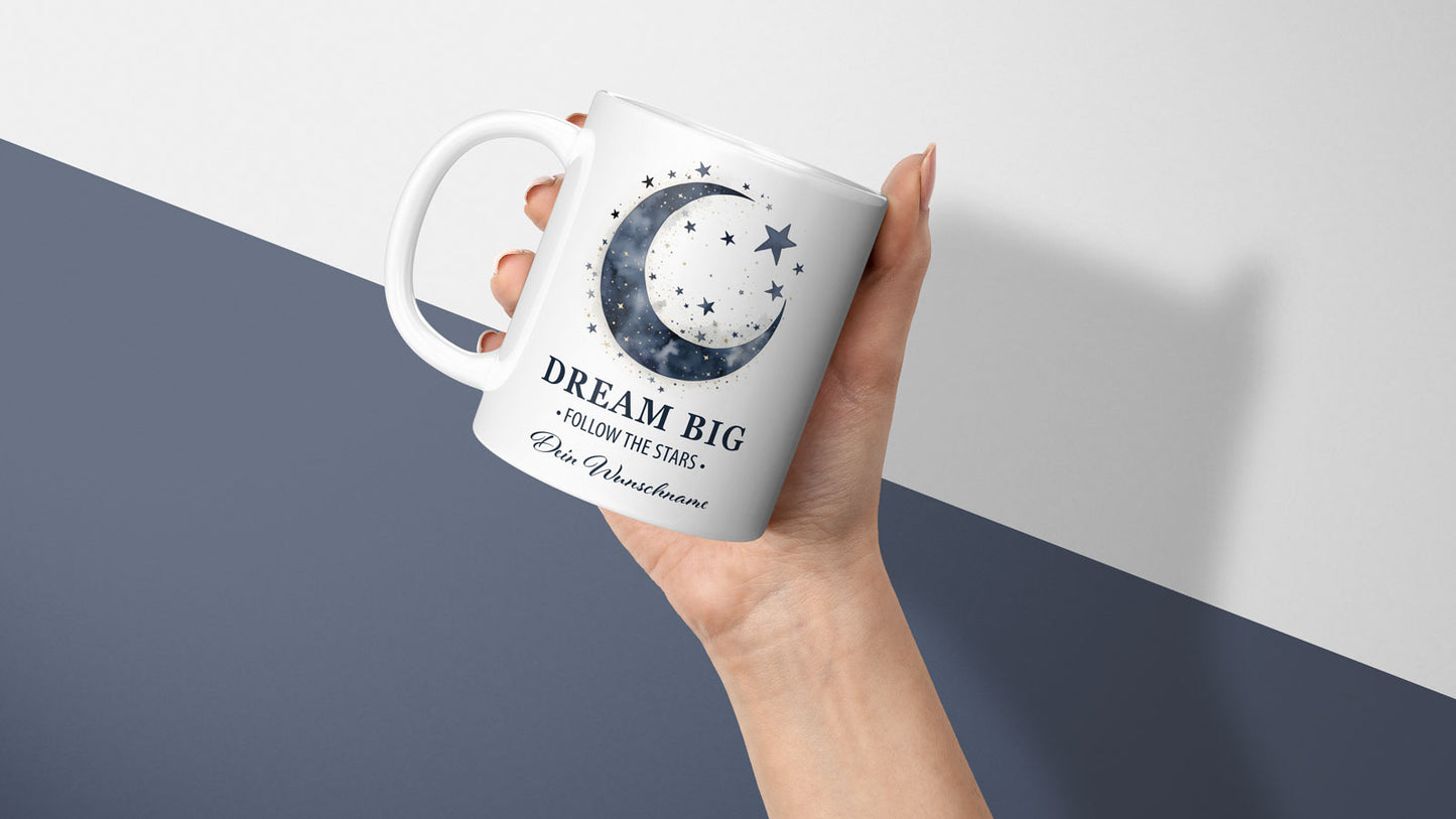 Weiße Kaffeetasse mit verträumtem Nachthimmel-Motiv: ein Halbmond, goldene Sterne und der Spruch „DREAM BIG – FOLLOW THE STARS“, mit Platz für einen Wunschname.