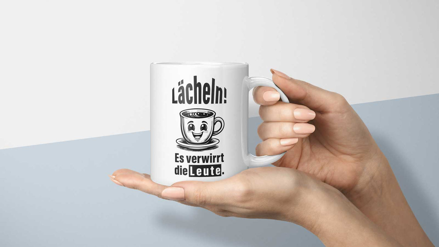 Detailaufnahme der Tasse mit schwarzem Text „Lächeln! Es verwirrt die Leute.“ und niedlichem Cartoon-Motiv.