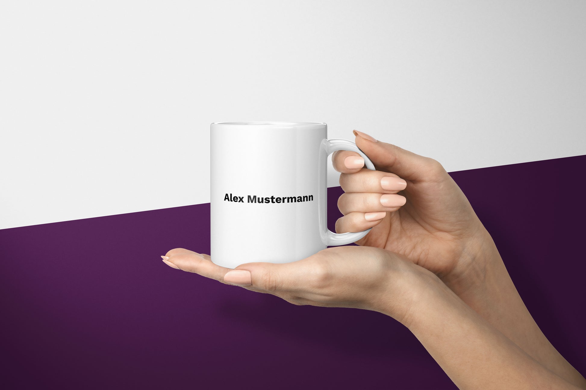 Damenhand stützt eine personalisierte Tasse am Henkel und hält sie auf der flachen Hand darunter, mit Schriftzug in Work Sans.